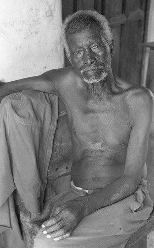 Man sits by a doorway, San Basilio de Palenque, 1975