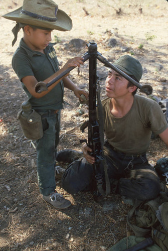 Child soldier helping to clean a machine gun, Usulután, El Salvador, 1982