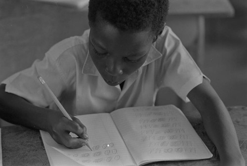 Student in a classroom writing on notebook, San Basilio de Palenque, ca. 1978