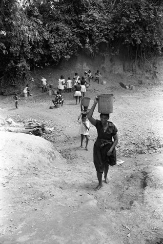 Woman walking with bucket on her head, San Basilio de Palenque, 1976