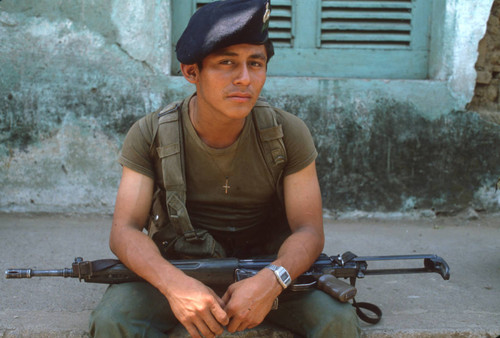 Soldier sitting on a sidewalk, Usulután, El Salvador, 1982