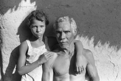 Man and girl standing in front of a house, San Basilio de Palenque, 1976