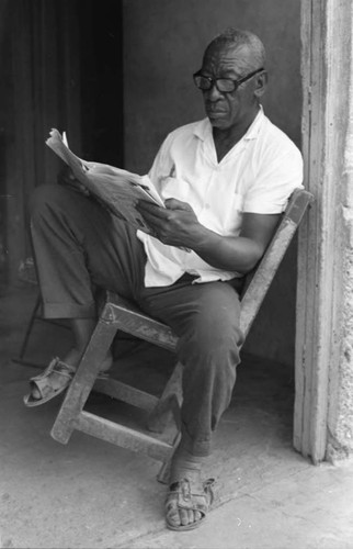 Fermín Herrera reading the newspaper, San Basilio de Palenque, 1975