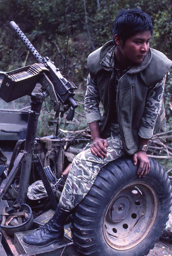 Young soldier sits on a tire while on patrol, Chichicastenango, 1982