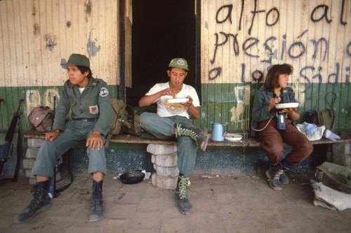 Guerrillas sitting on a bench and eating, San Agustín, 1983