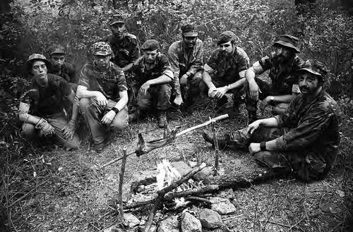 Survival school students sit around a campfire, Liberal, 1982