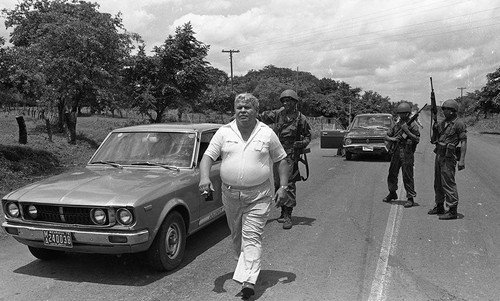 Three armed military men with M 16 guns stand on a road, Nicaragua, 1979