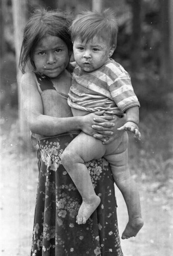 A girl holds a child in her arms in a refugee camp, Berlín, 1983