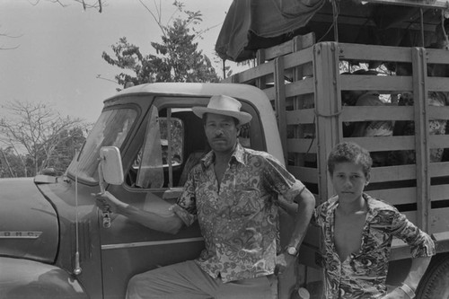 Man and boy stand in front of truck, San Basilio del Palenque, ca. 1978