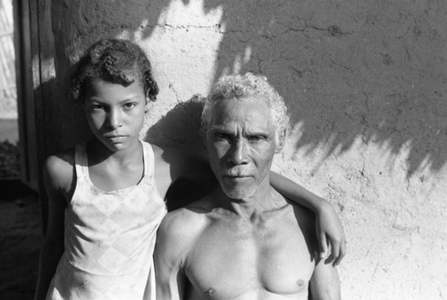 Man and girl standing in front of a house, San Basilio de Palenque, 1976