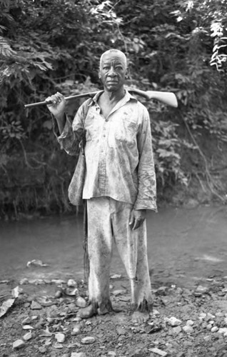 Fermín Herrera stands by the river with a rifle, San Basilio de Palenque, 1975