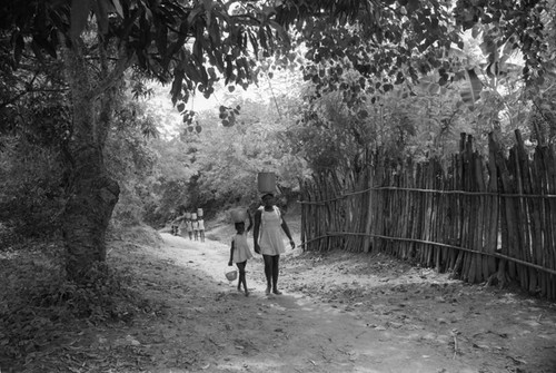 Woman and girl walking with buckets on their heads, San Basilio de Palenque, 1976