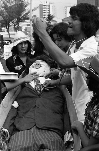 Man applying a stethoscope to a manikin in a coffin, Barranquilla, Colombia, 1977