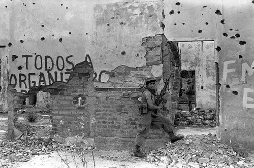 Army soldiers walk through ruins, Perquín, 1983