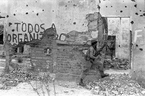 Army soldiers walk through ruins, Perquín, 1983