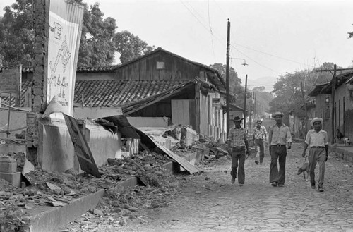 Four civilians walk through ruins, San Agustín, 1983