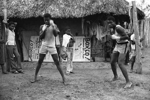 Two men boxing outdoor in front of a crowd, San Basilio de Palenque, 1975