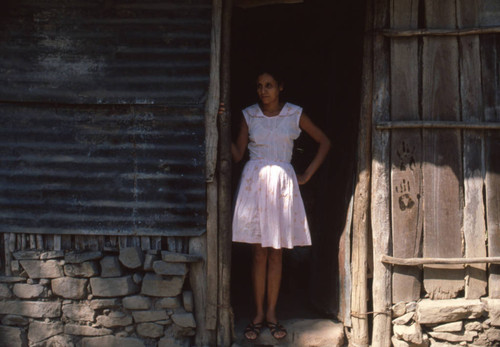 Woman standing outside a marked home, Meanguera, Morazán, El Salvador, 1981