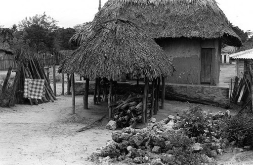 Pile of wood under a thatched roof structure, San Basilio de Palenque, 1976
