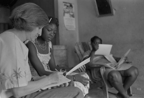 Nina S. de Friedemann and a woman looking at pictures, San Basilio del Palenque, ca. 1978