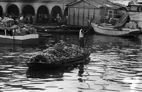 Man transports a load of bananas on a boat, Cartagena Province, 1975