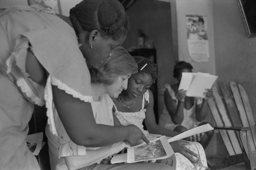 Nina S. de Friedemann and a woman looking at pictures, San Basilio del Palenque, ca. 1978