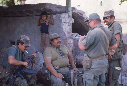 Salvadoran commander sits with soldiers, San Agustín, 1983