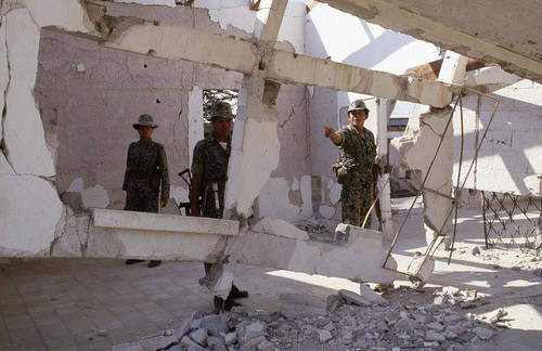 Soldiers stand near destroyed building, Guatemala, 1982