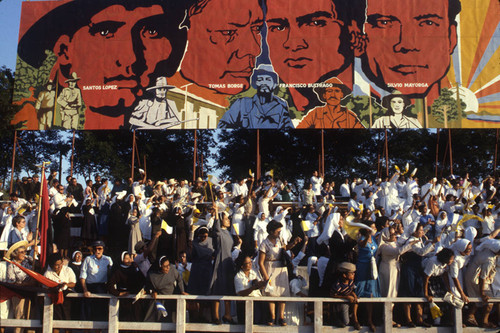 Large crowd cheers beneath a revolution mural, Managua, Nicaragua, 1983