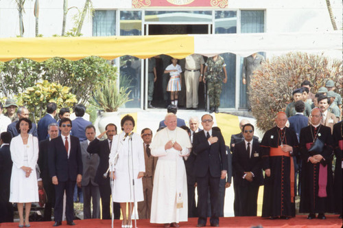 Pope John Paul II standing among clergy and officials, San Salvador, El Salvador, 1983