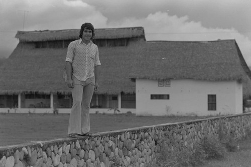 Young man standing on a stone fence, La Chamba, Colombia, 1975