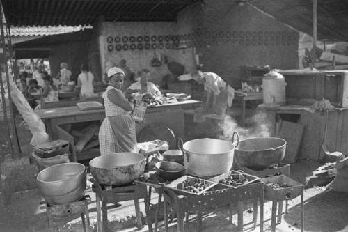 Woman stands next to cooking pots at city market, Cartagena Province, ca. 1978