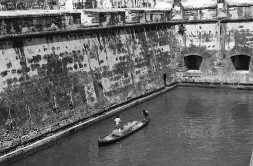 Man and boy navigating next to fortress, Cartagena, 1975