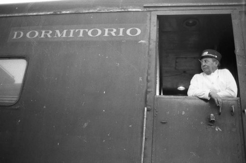 Railway porter peers out window of sleeping car, Chihuahua, 1983