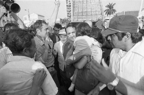 Duarte hugs a mother and child, San Salvador, 1982