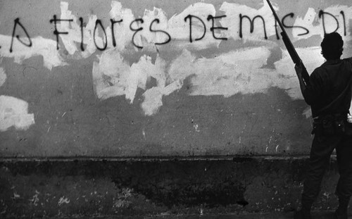 Sandinista walks near graffitied wall, Nicaragua, 1979