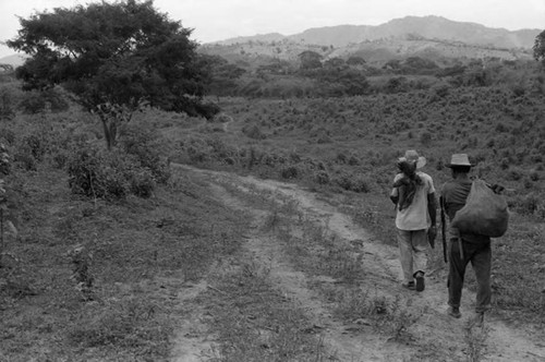 Two men carrying yucca roots, San Basilio de Palenque, 1975