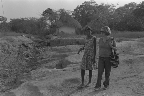 Nina S. de Friedemann walking with a women on a trail, San Basilio de Palenque, ca. 1978