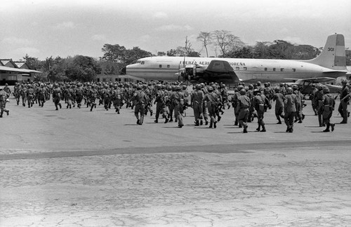 Salvadoran soldiers passing by airplanes at military base, Ilopango, 1983