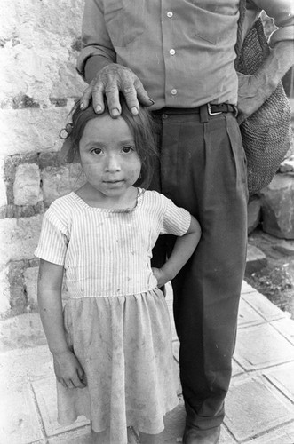 A man and a young girl stand by a building, Perquín, 1983