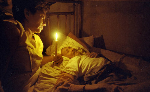 Woman with a candle next to a man in bed, Nicaragua, 1979