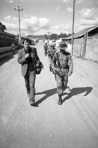 Richard Cross walks alongside soldier, Guatemala, 1982