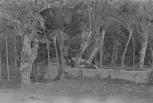 Man standing next to water flowing from a pipe, San Basilio de Palenque, ca. 1978