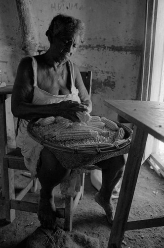 Woman removing corn from the cob, San Basilio de Palenque, 1976