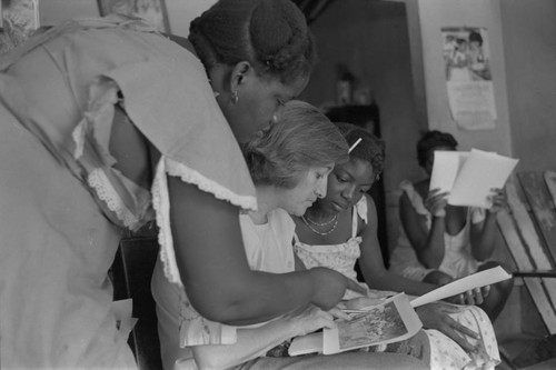 Nina S. de Friedemann and a woman looking at pictures, San Basilio del Palenque, ca. 1978