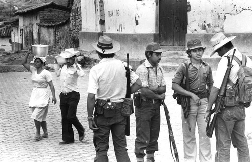 Guerrillas gather in the center of town and civilians walk by, Corinto, 1983