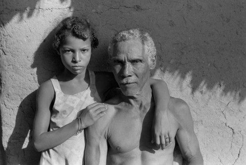 Man and girl standing in front of a house, San Basilio de Palenque, 1976