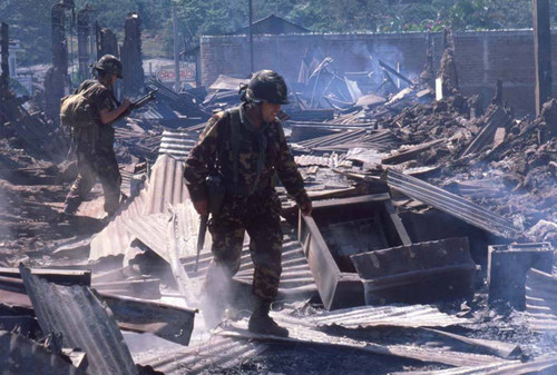 Salvadoran Army troops walk through debris after bombing, Berlín, 1983