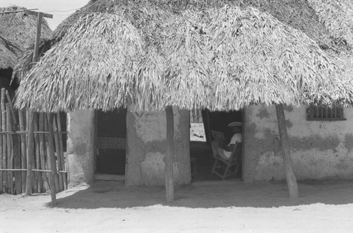 Man reading a newspaper inside a home, San Basilio de Palenque, 1976