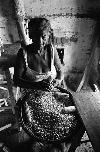 Woman removing corn from cobs, San Basilio de Palenque, 1976